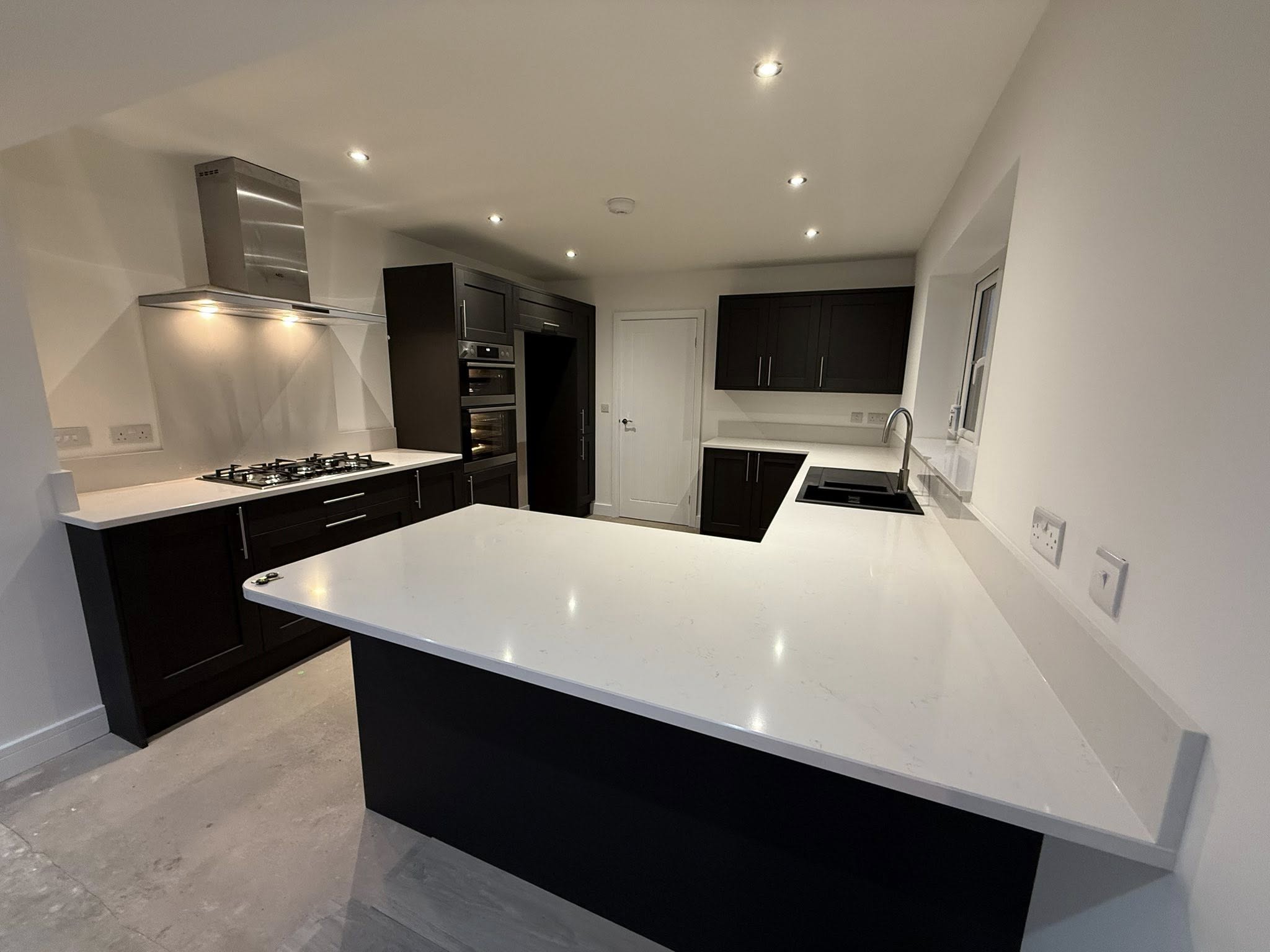 Contemporary dark kitchen with white quartz island